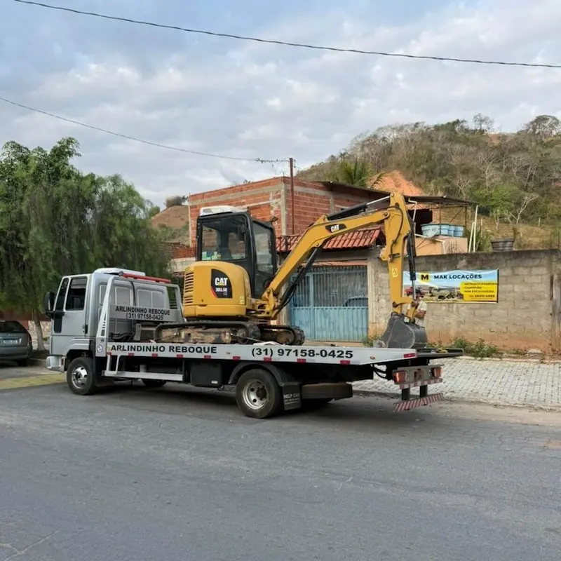 Transporte de máquina pesada (mini escavadeira amarela) realizado por guincho especializado.