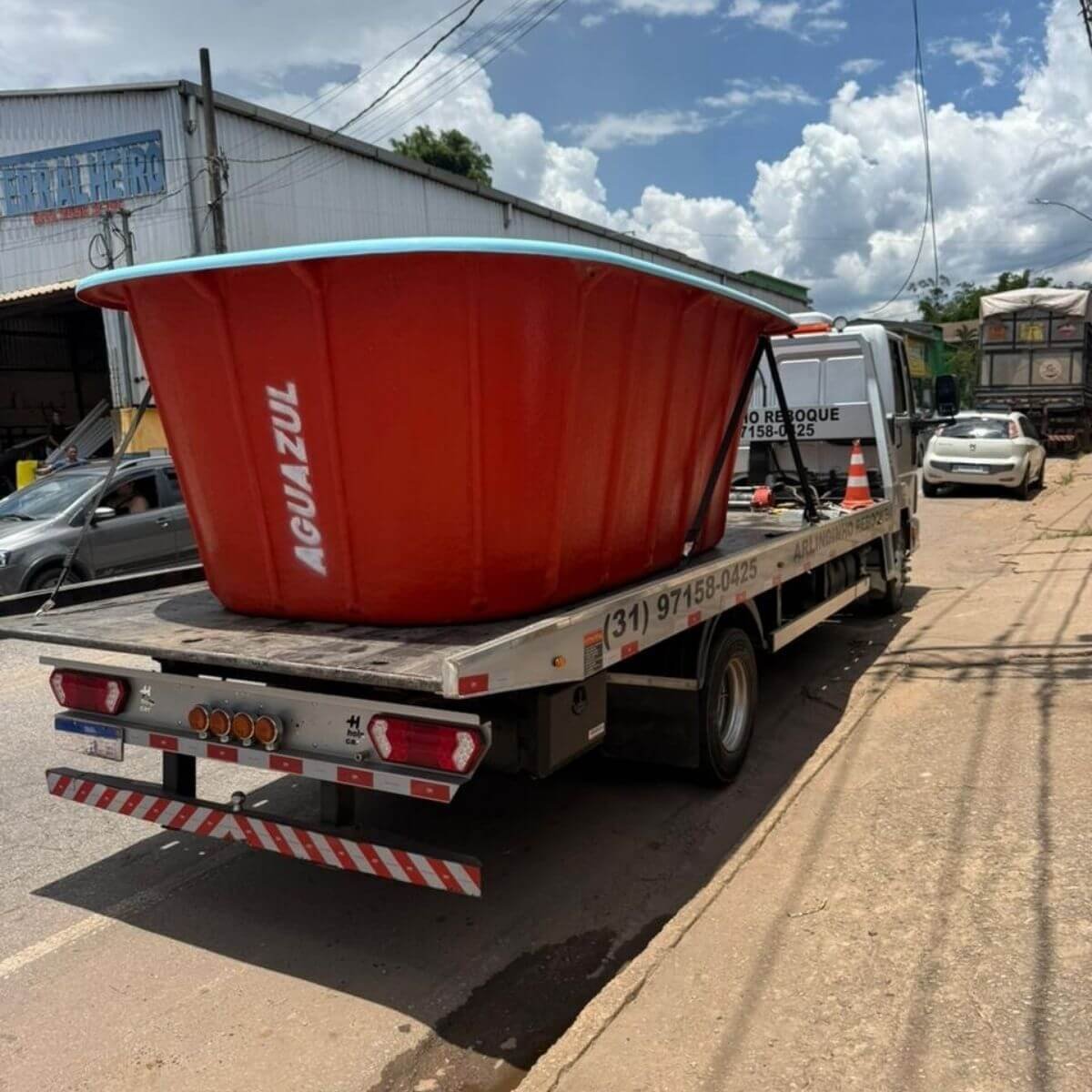 Transporte especializado de piscina de fibra vermelha em caminhão guincho.