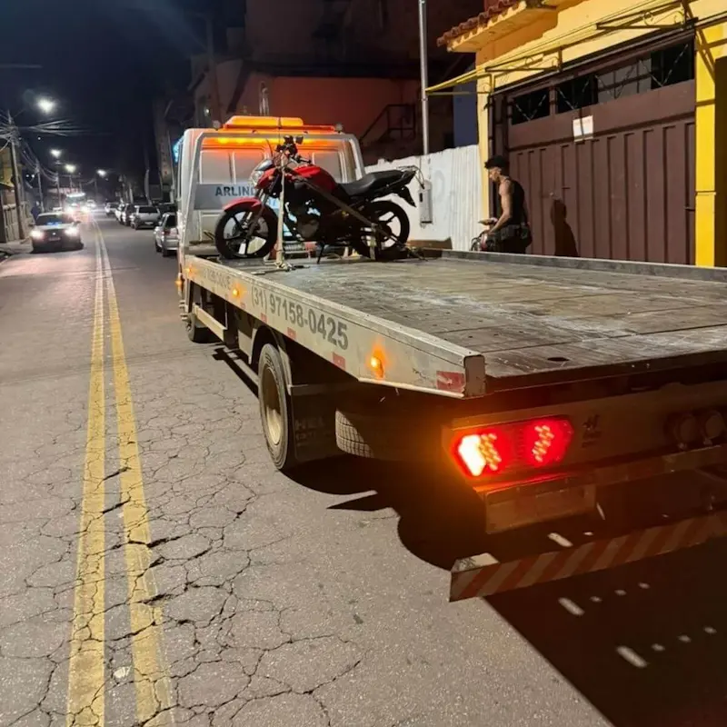 Resgate de motocicleta realizado à noite com cintas de segurança no guincho.