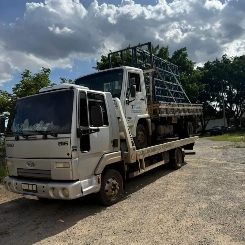 Guincho transportando estrutura de caminhão gaiola em dia nublado.
